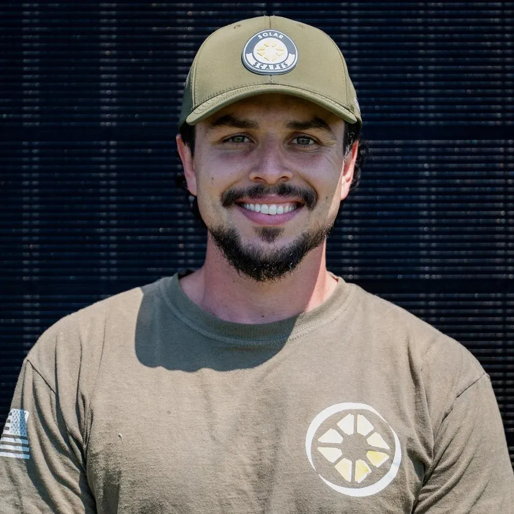 Cory B., Owner and Field Operator at Solar Scapes, smiling in front of solar panels